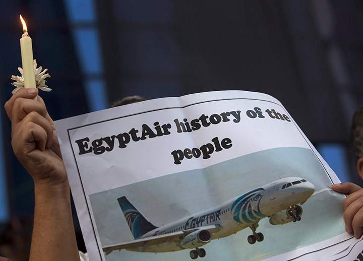 An Egyptian journalist holds a candle and a poster supporting EgyptAir during a candlelight vigil for the victims of EgyptAir flight 804 in front of the Journalists' Syndicate in Cairo, Egypt, Tuesday, May 24, 2016.