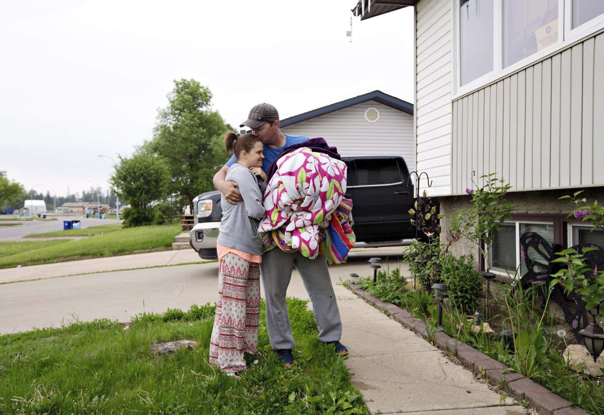 Mike Maloney and his wife Tessa Maloney, hug as they unpack to re-enter their home after being evacuated due to wildfires, in Fort McMurray Alta, on Wednesday June 1, 2016. Parts of Fort McMurray have been open for the public to go back home.