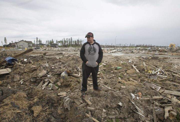 Resident Kenny Gibbons looks through his demolished backyard in the neighbourhood of Timberlea, in Fort McMurray, Alta, on Wednesday June 1, 2016. Residents began returning to their homes after being evacuated due to wildfires.