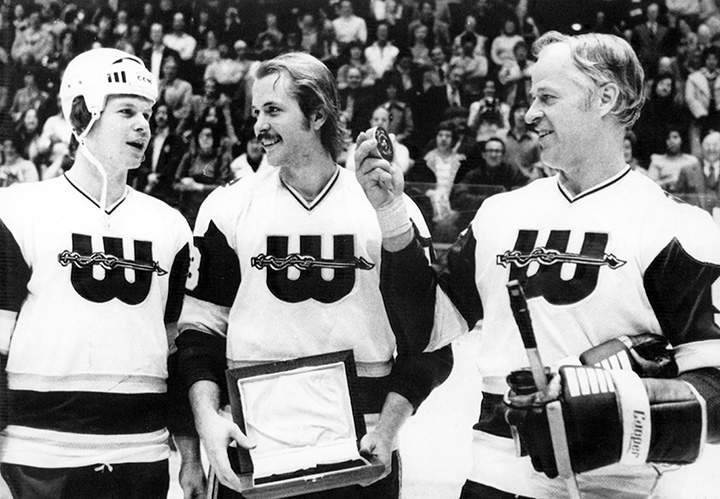 Gordie Howe of the Hartford Whalers of the World Hockey Association looks at a puck presented to him by his sons Mark (left) and Marty (centre) before a game in December 1977.