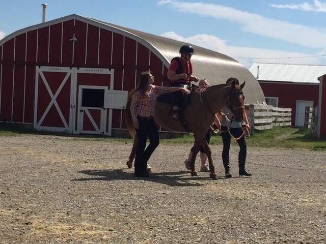 Maggie, a client of Opening Gaits rides Fleck and is watched closely by her two side-walkers.