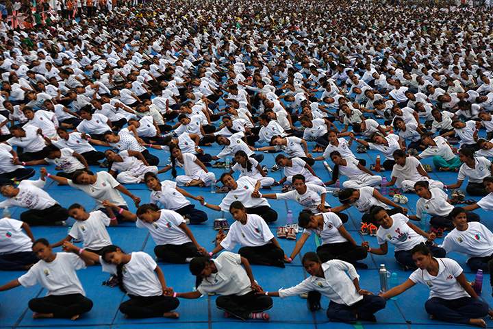 People holds hands as they attempt to create a record for the longest human yoga chain with more than 8000 participants at an event to celebrate International Yoga Day in Ahmadabad, India, Tuesday, June 21, 2016.