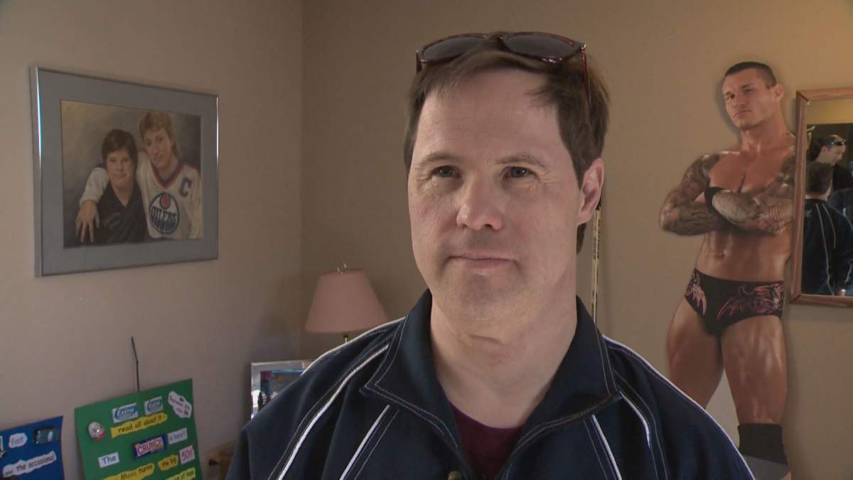 Joey Moss stands in front of a photo of Wayne Gretzky and himself. 