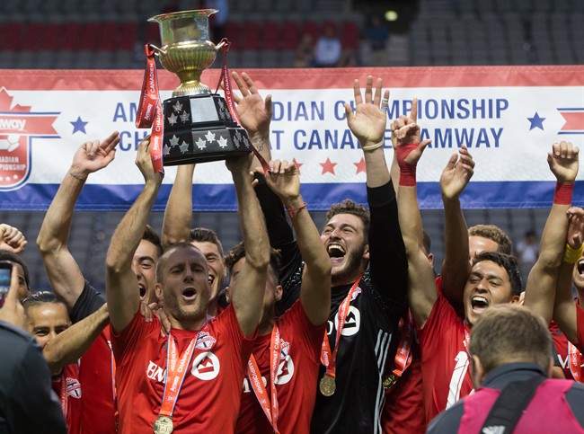 Toronto FC's Benoit Cheyrou, left, and his teammates celebrate with the Voyageurs Cup after defeating the Vancouver Whitecaps on aggregate in the Canadian Championship soccer final in Vancouver, B.C., on Wednesday June 29, 2016.