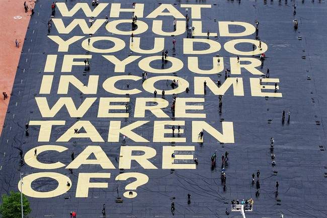 In this May 14, 2016 file picture a huge poster reading “What would you do if your income were taken care of?” is pictured on the Plaine de Plainpalais square in Geneva.
