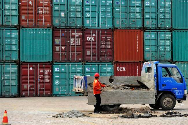 A worker repairs the ground at a container port in Qingdao in eastern China's Shandong province Wednesday, June 8, 2016.