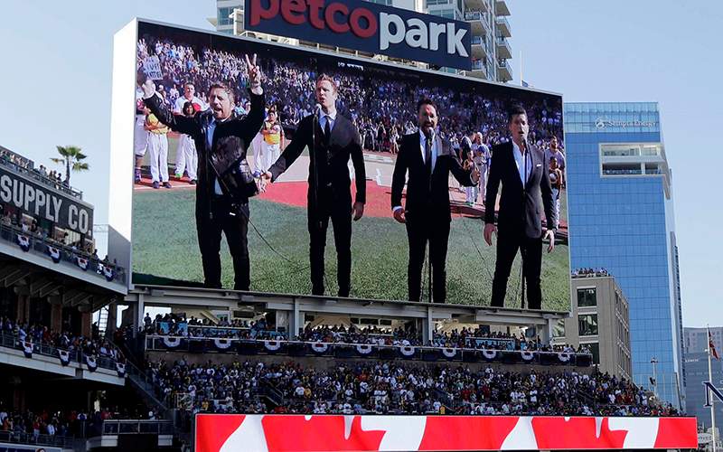 The Tenors, shown on the scoreboard, perform during the Canadian National Anthem prior to the MLB baseball All-Star Game, in San Diego. A member of a Canadian singing quartet changed a lyric in his country’s national anthem and held up a sign proclaiming “All Lives Matter” during a pregame performance at the 87th All-Star Game on Tuesday.