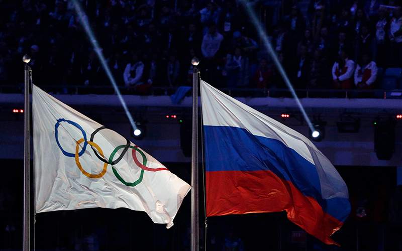 The Russian national flag flies next to the Olympic flag during the closing ceremony of the 2014 Winter Olympics in Sochi, Russia. 