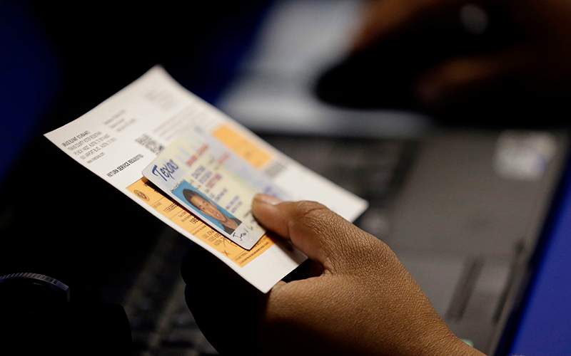 An election official checks a voter's photo identification at an early voting polling site in Austin, Texas on Feb. 26, 2014. 