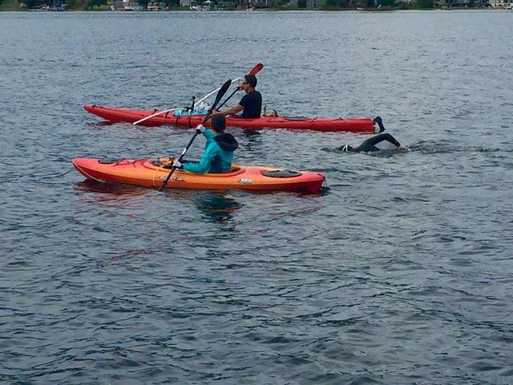Adam Ellenstein swims accompanied by members of his support crew.