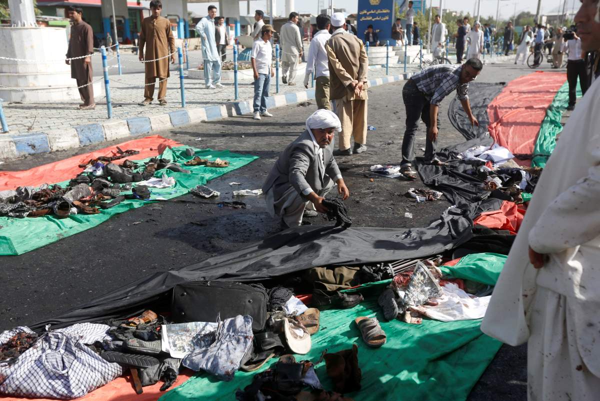 Afghan men remove the clothes of victims after a suicide attack in Kabul, Afghanistan July 23, 2016.