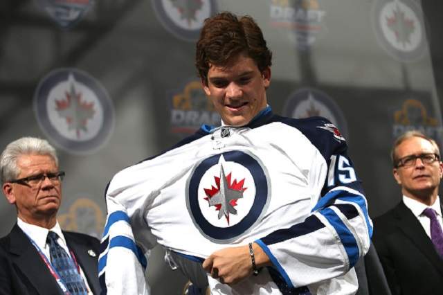 Jack Roslovic puts on a jersey after being selected 25th overall by the Winnipeg Jets during the first round of the 2015 NHL Draft at BB&T Center in Sunrise, Florida.