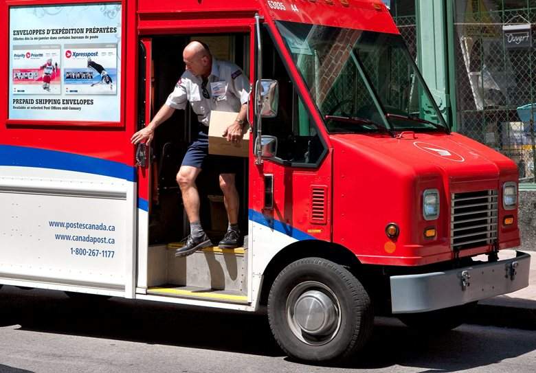 A Canada Post worker gets out of his delivery truck with a box in his hand in Quebec city June 15, 2009.