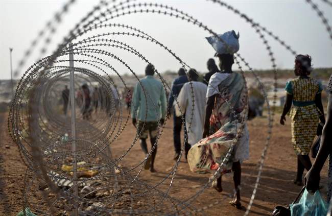 ,displaced people walk next to a razor wire fence at the United Nations base in the capital Juba, South Sudan on Jan. 19, 2016.