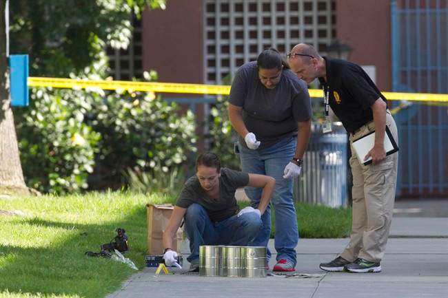 San Diego’s Metro Arson Strike Team and SDPD homicide team gather evidence from the sidewalk and grassy area where a homeless person was attacked in downtown San Diego.