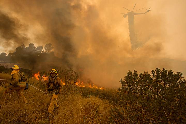 A firefighting helicopter makes a drop as firefighters step back from approaching flames in Placerita Canyon at the Sand Fire on July 24, 2016 in Santa Clarita, California.