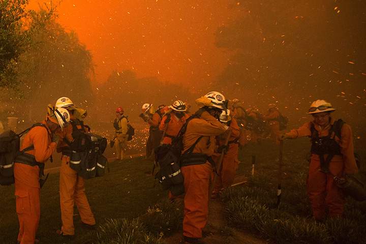 Firefighters shield themselves from embers and heavy smoke as flames close in on houses at the Sand Fire on July 23 2016 near Santa Clarita, California.