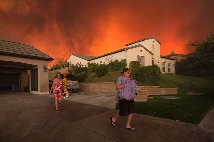Residents flee their home as flames from the Sand Fire close in on July 23 2016 near Santa Clarita, California.