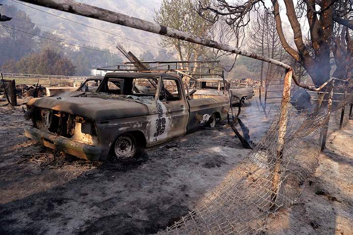 Burned-out vehicles and film sets are framed by a burned oak tree at Sable Ranch, which has Old West-style buildings used for movie locations in Santa Clarita, Calif., are seen Monday morning, July 25, 2016, after the massive Sand wildfire swept through the area over the weekend.