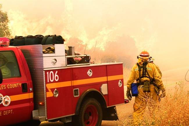 Los Angeles County firefighters watch brush fires on Placenta Canyon Road in Santa Clarita, Calif., Sunday, July 24, 2016. Flames raced down a steep hillside “like a freight train,” leaving smoldering remains of homes and forcing thousands to flee the wildfire churning through tinder-dry canyons in Southern California, authorities said Sunday. (AP Photo/Matt Hartman)
