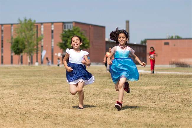 Children run back to their group after presenting flowers to other campers while attending Happi camp in Toronto on Tuesday July 12 , 2016.