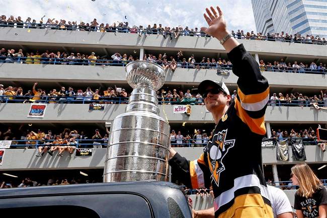 Pittsburgh Penguins' Sidney Crosby waves to the crowd while holding onto the Stanley Cup while riding along the victory parade route in Pittsburgh, Pa., Wednesday, June 15, 2016. Sidney Crosby is bringing the Stanley Cup back to Nova Scotia.The official Twitter account for Crosby's hockey school announced Wednesday that the Pittsburgh Penguins captain would return the Stanley Cup to Cole Harbour, N.S., on July 16.