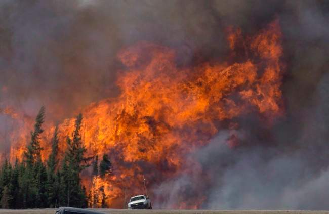 A giant fireball is seen as a wildfire rips through the forest 16 kilometres south of Fort McMurray, Alta. on Highway 63 Saturday, May 7, 2016. 