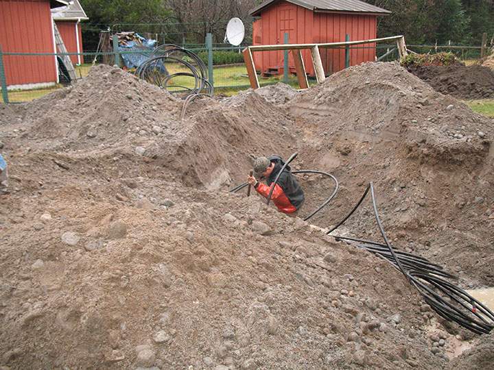 Contractors install the ground tubing of the geothermal heating system in an excavation on the south side of a home in the Mendenhall Valley area of Juneau, Alaska.