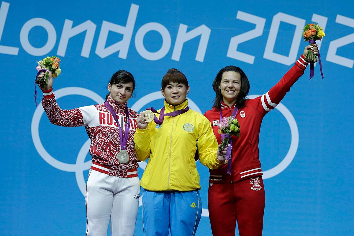 Gold medalist Maiya Maneza of Kazakhstan, center, stands with silver medalist Svetlana Tsarukaeva of Russia, left, and bronze medalist Christine Girard of Canada during a medals ceremony after the women's 63-kg, weightlifting competition at the 2012 Summer Olympics, Tuesday, July 31, 2012, in London. 