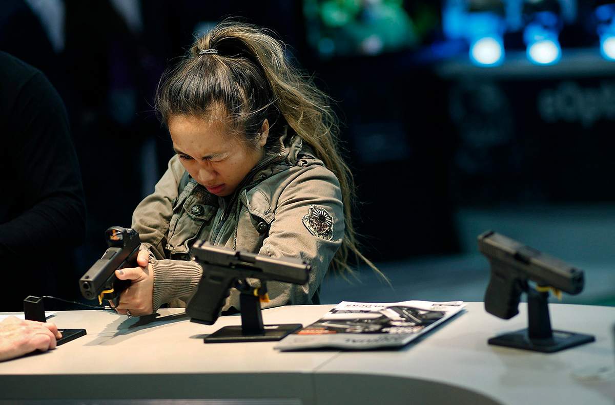 In this Jan. 19, 2016 file photo, a woman looks at a handgun at the Glock booth at the Shooting Hunting and Outdoor Trade Show in Las Vegas.
