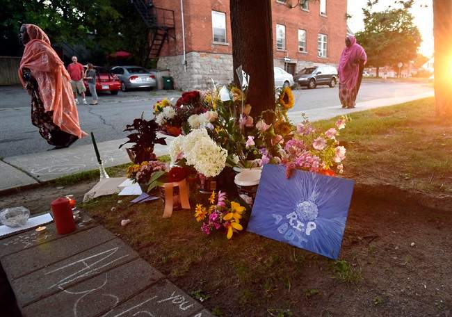 Mourners arriving for a memorial pass flowers laid outside the apartment where Abdirahman Abdi lived and was fatally injured after being arrested by Ottawa Police officers.