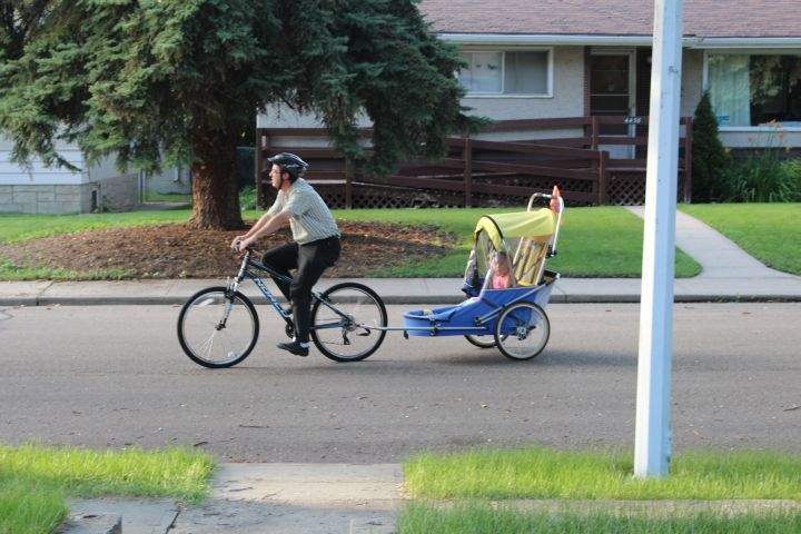 Vienna Lewin’s father tows her on a trailer attached to his bicycle.