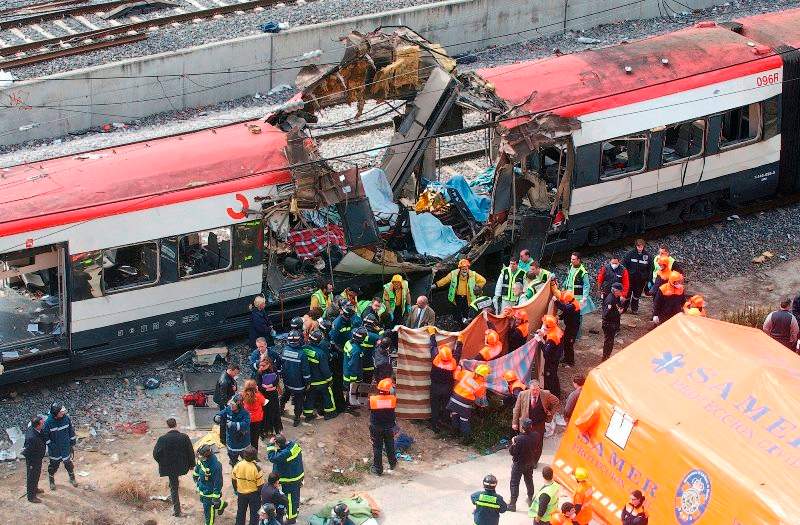 Rescue workers cover up bodies alongside a bomb-damaged passenger train, following a number of explosions in Madrid, Spain, in this March 11, 2004 file photo. (AP Photo/Paul White)