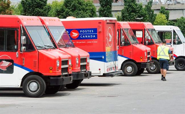 A postal worker walks past Canada Post trucks at a sorting centre in Montreal, Friday, July 8, 2016.
