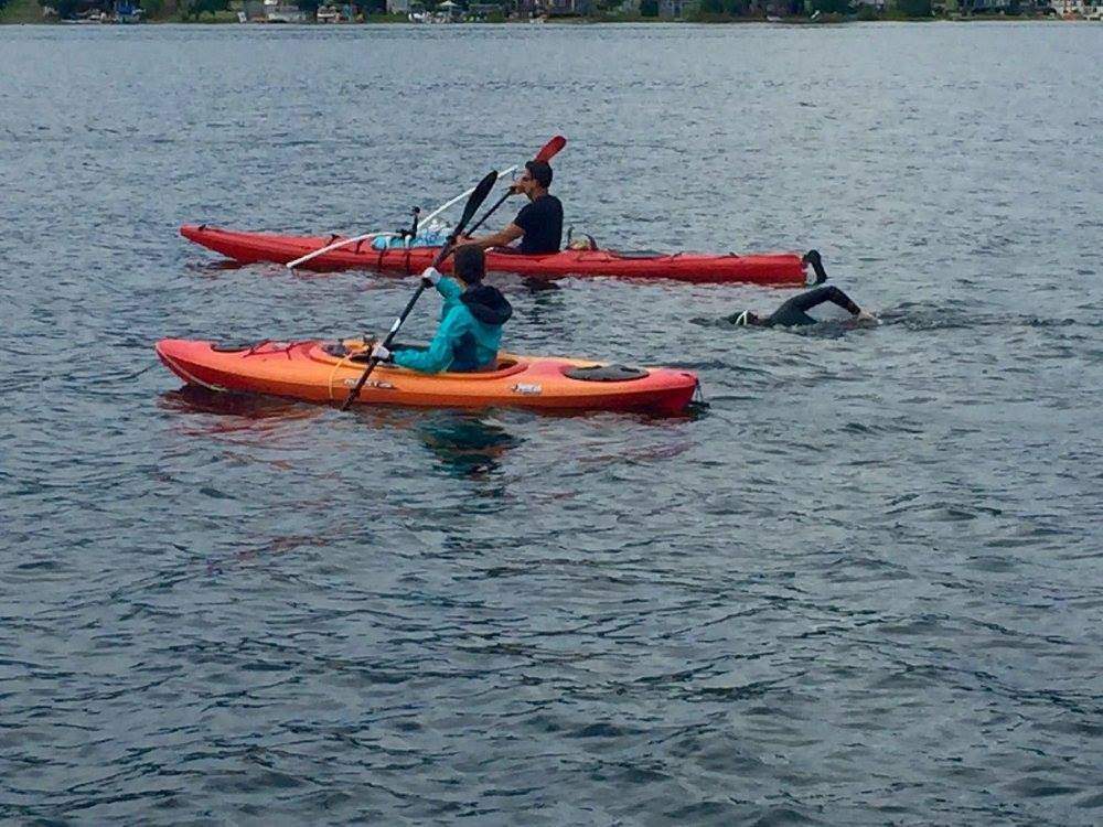 Adam Ellenstein swims accompanied by members of his support crew.