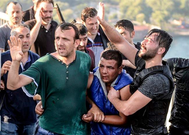People apprehend a Turkish soldier, center in blue, that participated in the attempted coup, on Istanbul's Bosporus Bridge, Saturday, July 16, 2016.