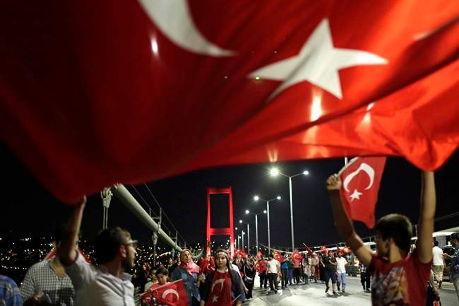 Pro-government supporters wave a Turkish flag as they protest on Istanbul's iconic Bosporus Bridge, late Thursday, July 21, 2016. Turkish lawmakers approved a three-month state of emergency, endorsing new powers for Turkey's President Recep Tayyip Erdogan that would allow him to expand a crackdown that has already included mass arrests and the closure of hundreds of schools, in the wake of the July 15 failed coup.