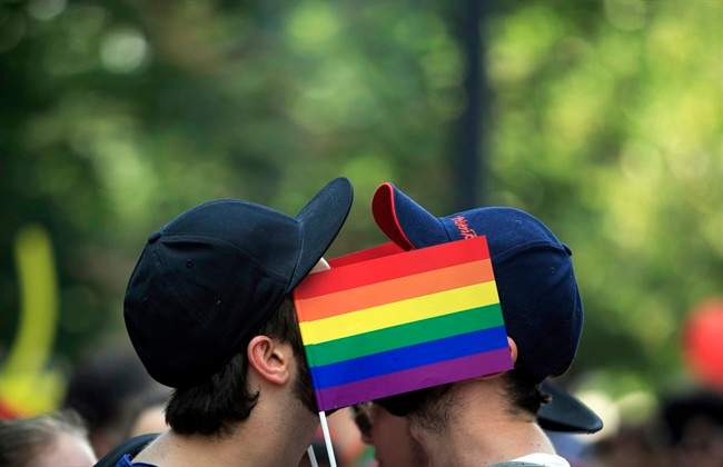 Men cover their faces with rainbow flags during a gay pride parade in Bucharest, Romania. 