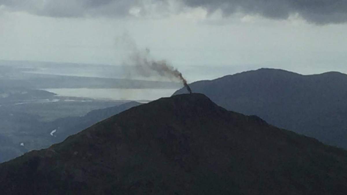 In this image provided by The National Trust, a thick plume of smoke rises from Yr Aran after a helicopter made an emergency landing in north Wales, Tuesday Aug. 9, 2016.  