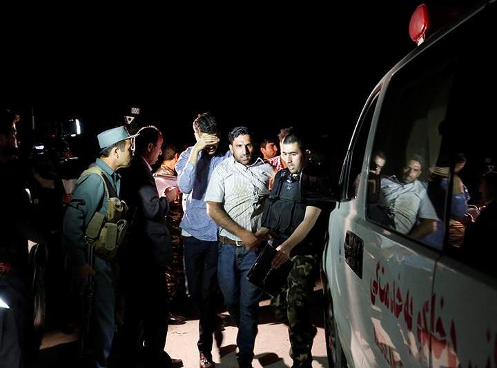 Men walk towards an ambulance after they were rescued from the site of an attack at American University of Afghanistan in Kabul, August 24, 2016.