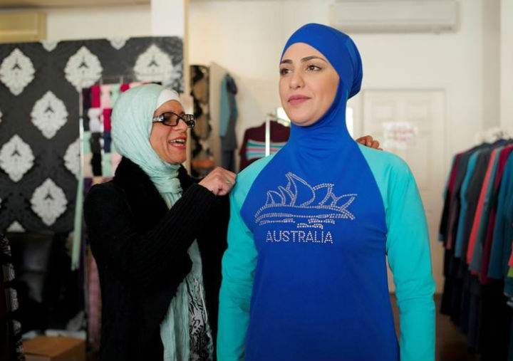 Aheda Zanetti (L), designer of the Burkini swimsuit, adjusts one of the swimsuits on model Salwa Elrashid at her fashion store in Sydney, August 23, 2016.