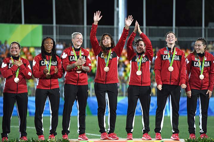 Members of Canada’s women’s rugby sevens team wave to fans during the medal ceremony after winning the bronze medal against Great Britain at the 2016 Olympic Games in Rio de Janeiro, Brazil on Monday, Aug. 8, 2016.