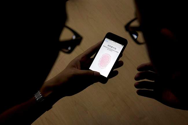 Canada's police chiefs want a new law that would force people to hand over their computer passwords with a judge's consent. In this September 11, 2013, file photo, an Apple employee, right, instructs a journalist on the use of the fingerprint scanner technology built into the company's iPhone 5S during a media event in Beijing.