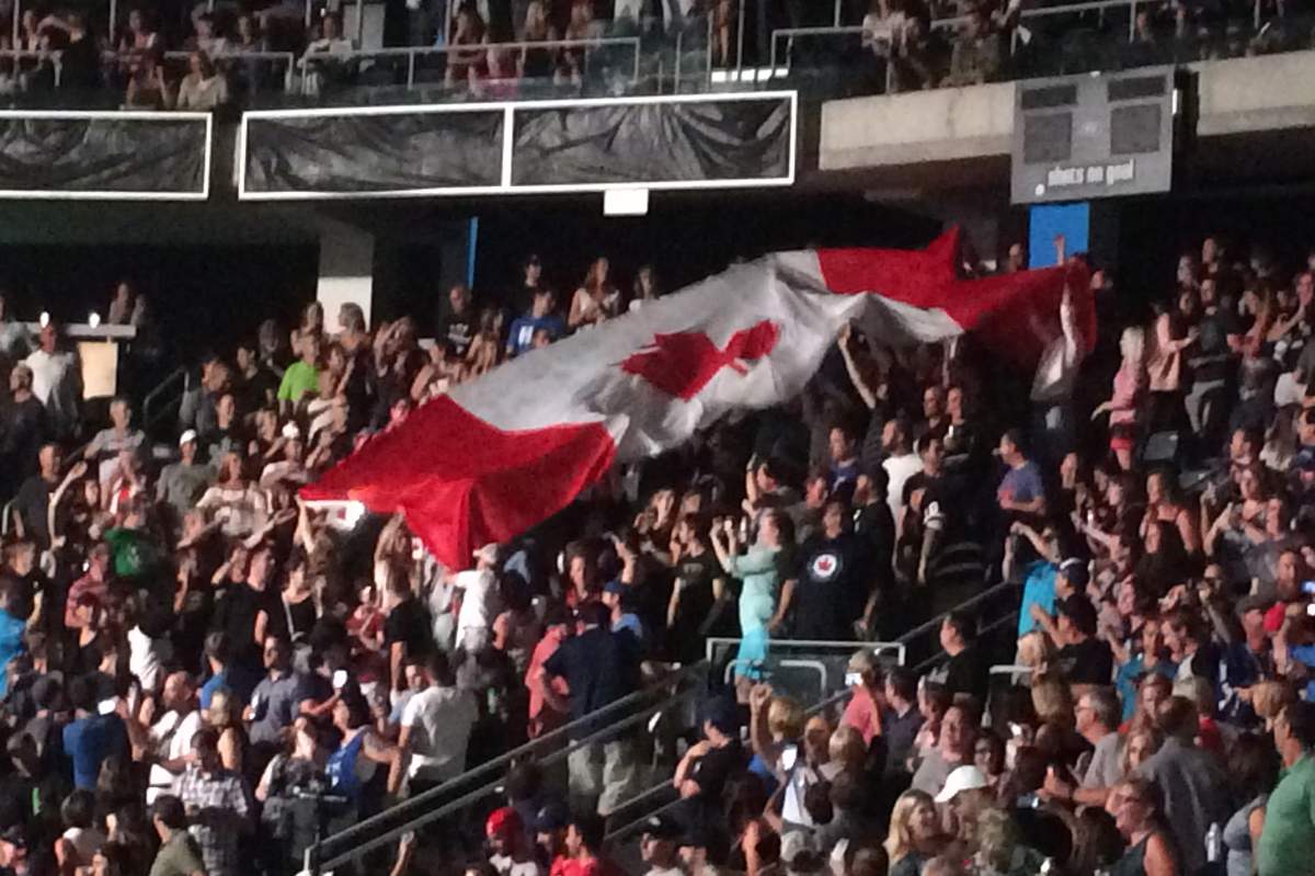 A large Canadian flag being passed through the crowd as concertgoers wait for the show to go on.