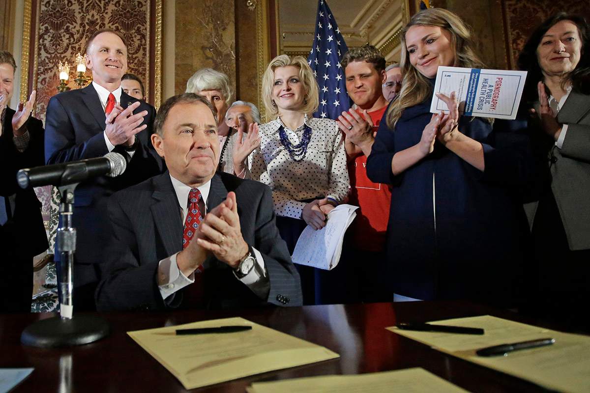 In this April 19, 2016, file photo, Utah Gov. Gary Herbert and supporters applaud during a ceremonial signing of a state resolution declaring pornography a public health crisis in Salt Lake City, Utah. 