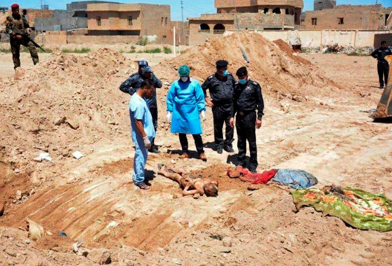 In this April 19, 2016 file photo, an Iraqi security forces forensic team works at the site of a mass grave believed to contain the bodies of Iraqi civilians, security forces and members of their families, including women and children, killed by Islamic State group militants at the stadium area in Ramadi, Iraq. (AP Photo, File)