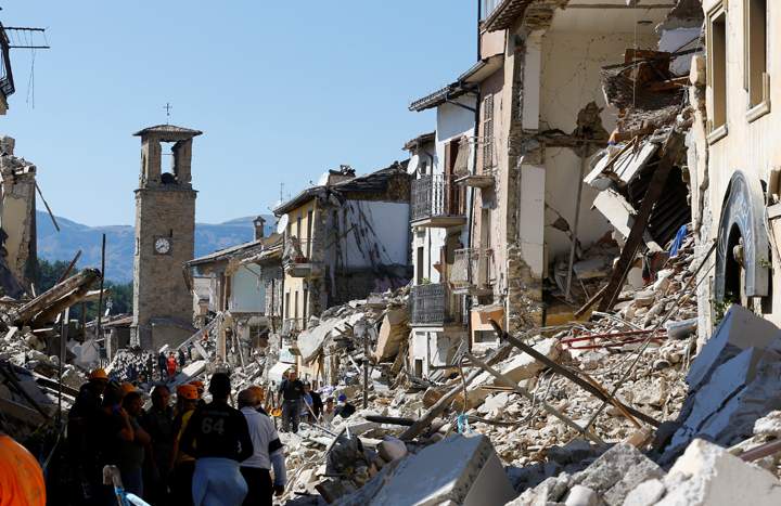 People stand next collapsed buildings following an earthquake in Amatrice, central Italy, August 24, 2016.
