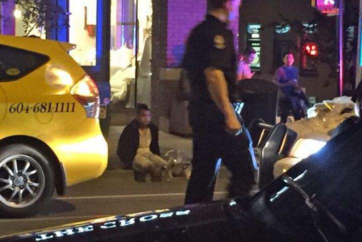 Louie Mojica sits on a Vancouver sidewalk after being arrested by police in May 2016.