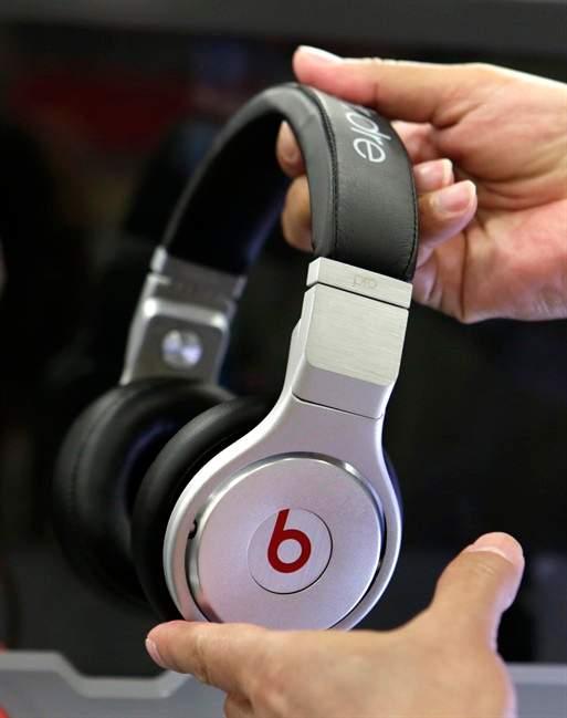 In this Thursday, May 29, 2014, file photo, a customer holds a pair of Beats headphones at a Best Buy store in Hialeah, Fla.