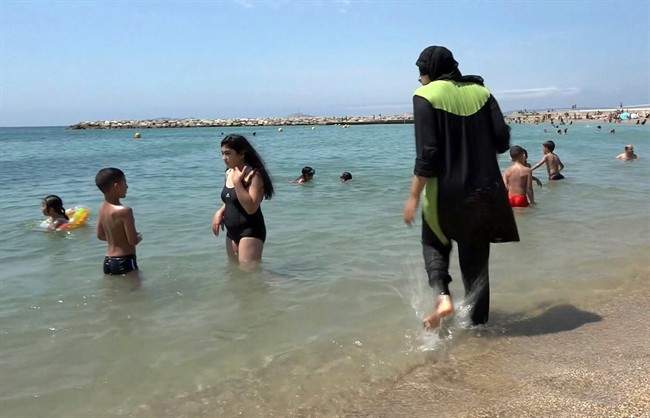 FILE - In this Aug.4 2016 file photo made from video, Nissrine Samali, 20, gets into the sea wearing traditional Islamic dress, in Marseille, southern France. The French resort of Cannes has banned full-body, head-covering swimsuits worn by some Muslim women from its beaches, citing security concerns. A City Hall official said the ordinance, in effect for August, could apply to burkini-style swimsuits. (AP Photo, File).